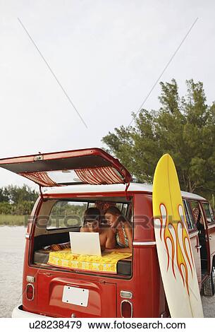 Young couple using laptop in van on beach View Large Photo Image Stock Photo - Young couple using laptop in van on beach. Fotosearch