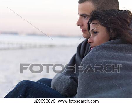 Young couple wrapped in blankets on beach View Large Photo Image Stock Image - Young couple wrapped in blankets on beach. Fotosearch