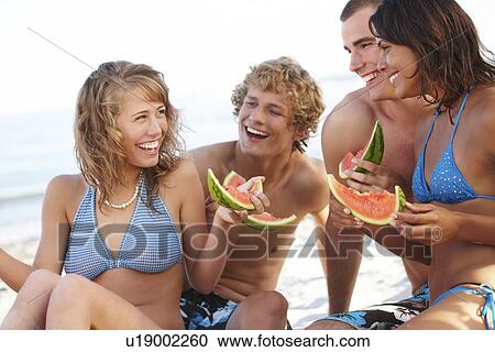 Young couples eating watermelon on beach View Large Photo Image Stock Image - Young couples eating watermelon on beach. Fotosearch