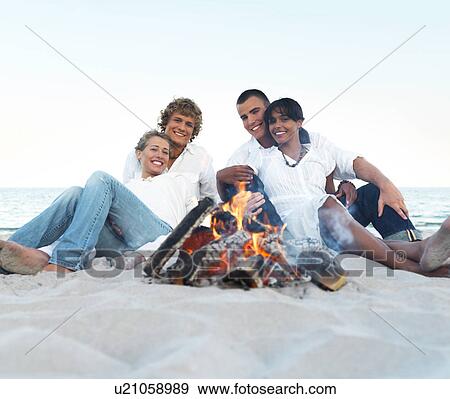 Young couples hugging by campfire on beach View Large Photo Image Stock Photo - Young couples hugging by campfire on beach. Fotosearch