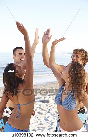 Young friends high fiving on beach View Large Photo Image Stock Image - Young friends high fiving on beach. Fotosearch