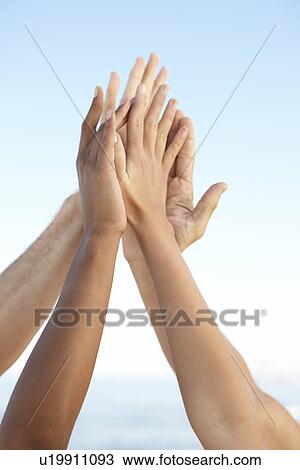 Stock Image - Young friends high fiving on beach. Fotosearch