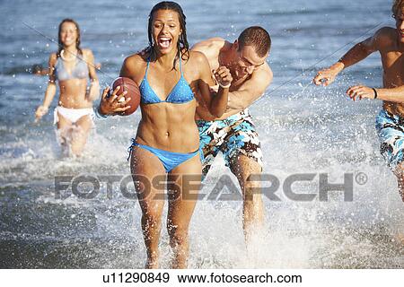 Young friends playing football in ocean View Large Photo Image Stock Photo - Young friends playing football in ocean. Fotosearch