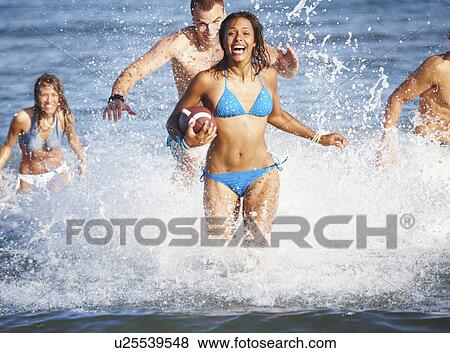 Young friends playing football in ocean View Large Photo Image Stock Photo - Young friends playing football in ocean. Fotosearch