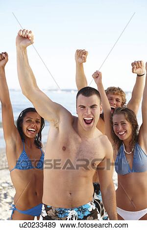 Stock Photo - Young friends raising arms on beach. Fotosearch