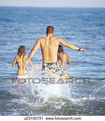 Young friends running into ocean View Large Photo Image Stock Image - Young friends running into ocean. Fotosearch