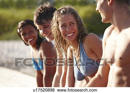 Stock Photo - Young friends sitting on dock. Fotosearch