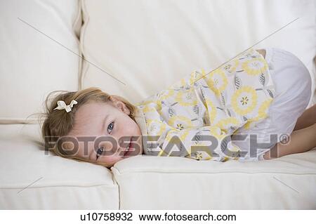 Stock Image - Young girl laying on sofa. Fotosearch