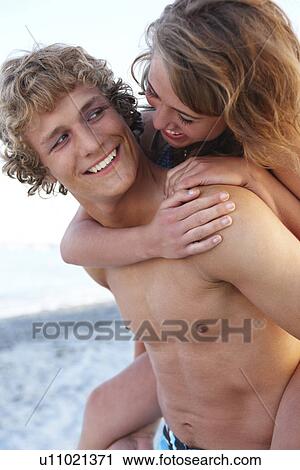 Stock Image - Young man carrying girlfriend on back. Fotosearch
