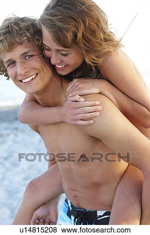 Stock Photo - Young man carrying girlfriend on back. Fotosearch