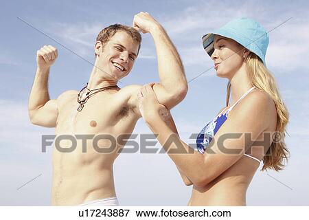 Stock Photo - Young man flexing muscles for girlfriend. Fotosearch