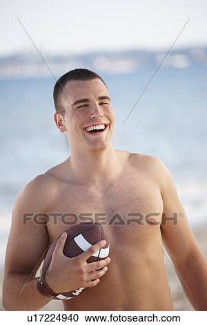 Young man holding football on beach View Large Photo Image Stock Image - Young man holding football on beach. Fotosearch