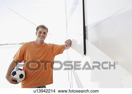 Picture - Young man leaning against motor home. Fotosearch