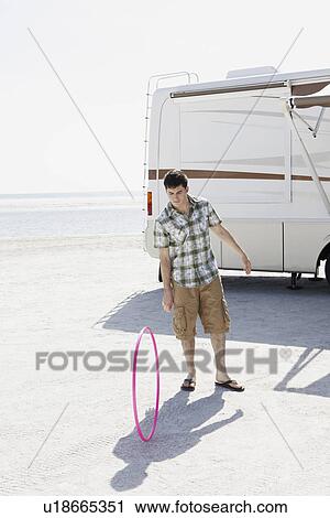Young man spinning hula hoop on beach View Large Photo Image Stock Image - Young man spinning hula hoop on beach. Fotosearch