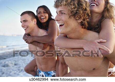 Young men carrying girlfriends on backs View Large Photo Image Picture - Young men carrying girlfriends on backs. Fotosearch