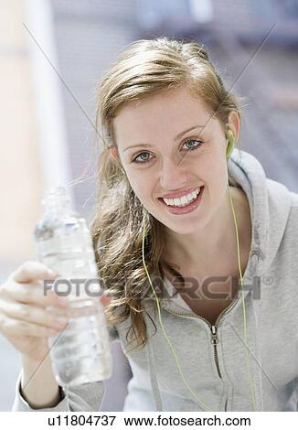 Stock Photo - Young woman drinking water after workout. Fotosearch
