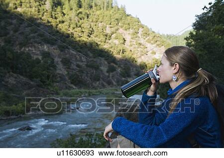 Young woman drinking water on river overlook View Large Photo Image Stock Image - Young woman drinking water on river overlook. Fotosearch