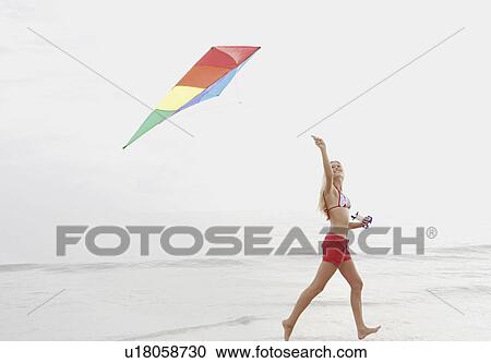 Young woman flying kite on beach View Large Photo Image Stock Image - Young woman flying kite on beach. Fotosearch