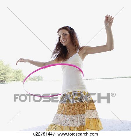 Stock Photo - Young woman hula hooping on beach. Fotosearch
