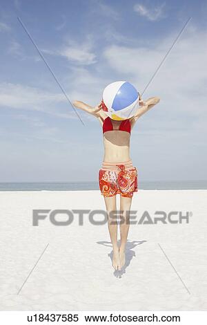 Stock Photography - Young woman jumping with beach ball. Fotosearch