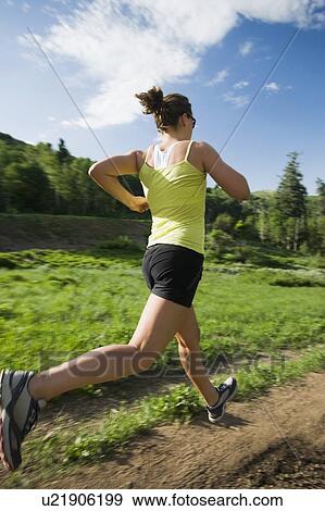 Stock Photo - Young woman running on trail. Fotosearch