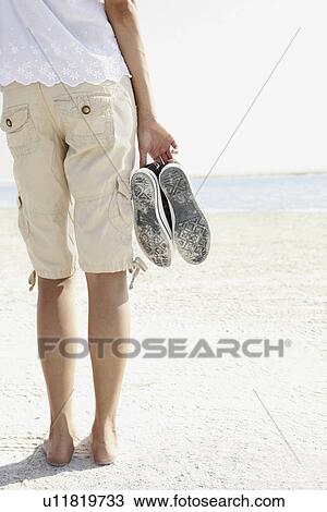 Young woman walking barefoot on beach View Large Photo Image Stock Image - Young woman walking barefoot on beach. Fotosearch