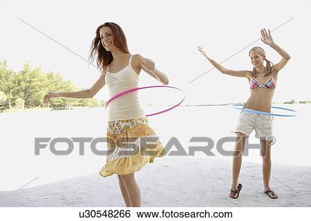 Stock Photograph - Young women hula hooping on beach. Fotosearch
