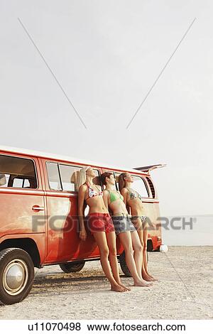 Young women leaning against van on beach View Large Photo Image Stock Photo - Young women leaning against van on beach. Fotosearch