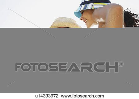 Stock Image - Young women whispering. Fotosearch