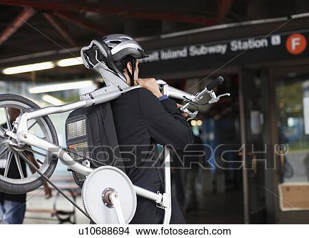 Picture - Businessman Carrying Bicycle to Subway Station. Fotosearch