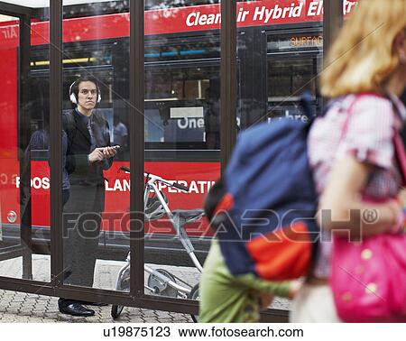 Businessman Listening to MP3 Player at Bus Stop View Large Photo Image Stock Image - Businessman Listening to MP3 Player at Bus Stop. Fotosearch