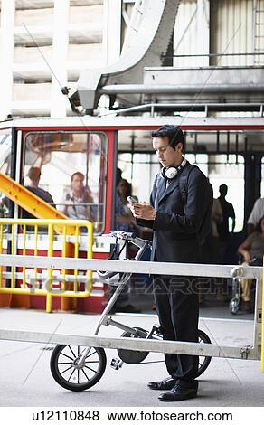 Stock Photo - Businessman Using Cell Phone at Station. Fotosearch