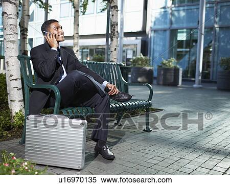 Stock Photography - Businessman Using Cell Phone on Bench. Fotosearch