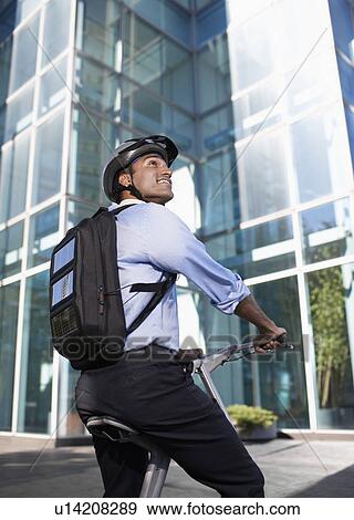 Stock Photo - Businessman with Solar Panelled Backpack on Folding Bike. Fotosearch