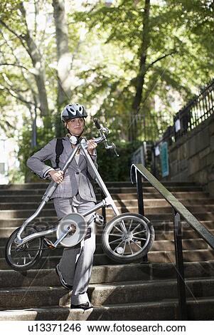 Stock Photograph - Businesswoman Carrying Bike on Steps. Fotosearch
