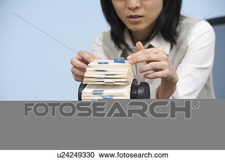 Stock Image - Businesswoman Going Through Rotary Card File. Fotosearch