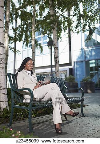 Stock Photo - Businesswoman Using PDA on Bench. Fotosearch