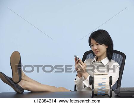 Businesswoman with Feet on Desk Using Cell Phone View Large Photo Image Picture - Businesswoman with Feet on Desk Using Cell Phone . Fotosearch