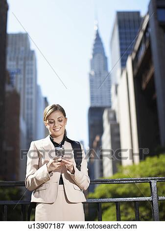 Mid-Adult Businesswoman Text Messaging near Skyscrapers View Large Photo Image Stock Photo - Mid-Adult Businesswoman Text Messaging near Skyscrapers. Fotosearch