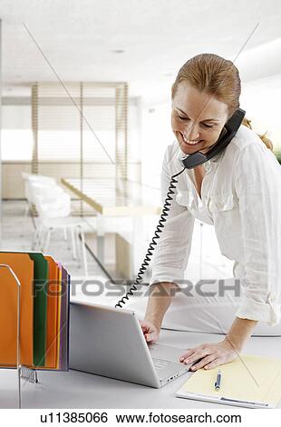 Mid-Adult Businesswoman Using Telephone and Laptop View Large Photo Image Stock Photograph - Mid-Adult Businesswoman Using Telephone and Laptop. Fotosearch