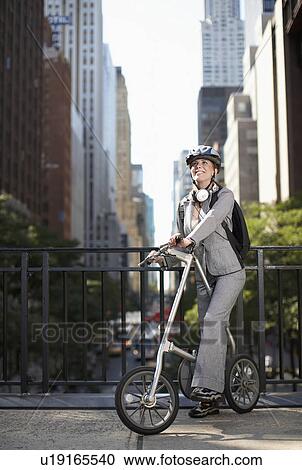 Stock Image - Mid-Adult Businesswoman with Bicycle. Fotosearch