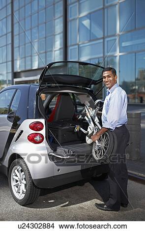 Mid-Adult Man Putting Folding Bike into Car Trunk View Large Photo Image Picture - Mid-Adult Man Putting Folding Bike into Car Trunk. Fotosearch