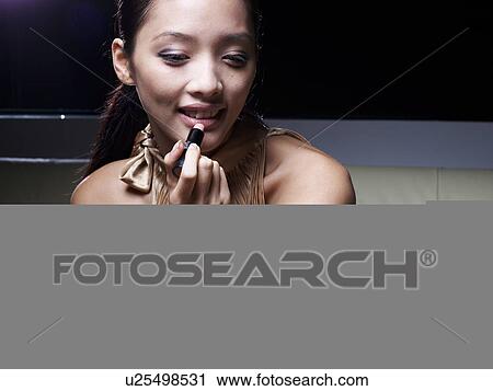 Stock Image - Mid-Adult Woman Applying Lipstick. Fotosearch