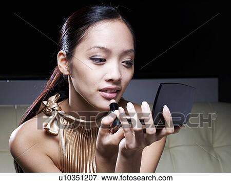 Stock Photo - Mid-Adult Woman Applying Lipstick. Fotosearch