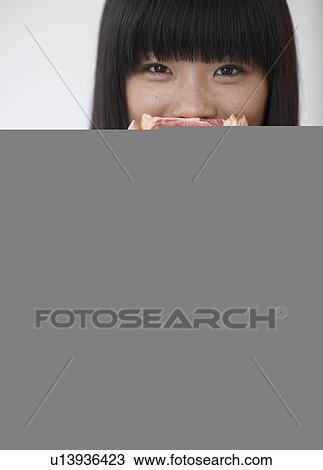 Stock Image - Mid-Adult Woman Eating Pink Grapefruit. Fotosearch