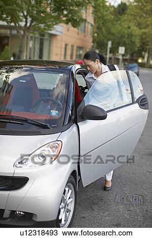 Stock Image - Mid-Adult Woman Getting Into Smart Car. Fotosearch