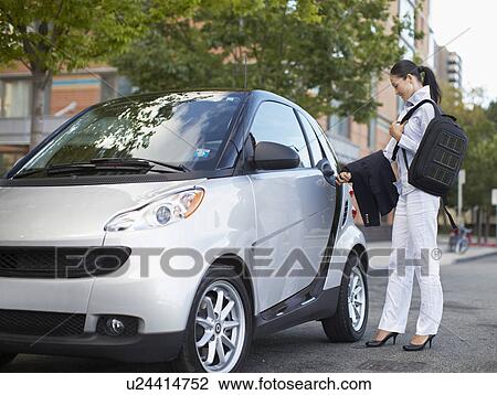 Stock Image - Mid-Adult Woman Getting Into Smart Car. Fotosearch