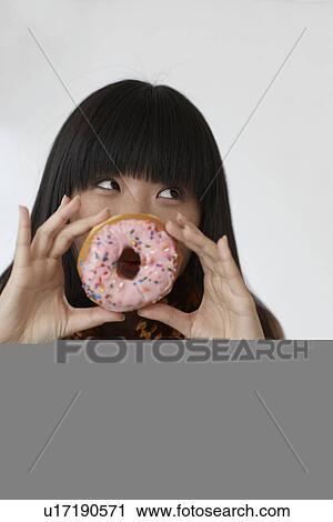 Stock Image - Mid-Adult Woman Holding Donut In Front Of Mouth. Fotosearch
