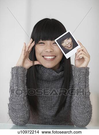 Picture - Mid-Adult Woman Holding Photograph of Herself. Fotosearch