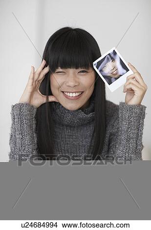 Mid-Adult Woman Holding Photograph of Herself View Large Photo Image Picture - Mid-Adult Woman Holding Photograph of Herself. Fotosearch
